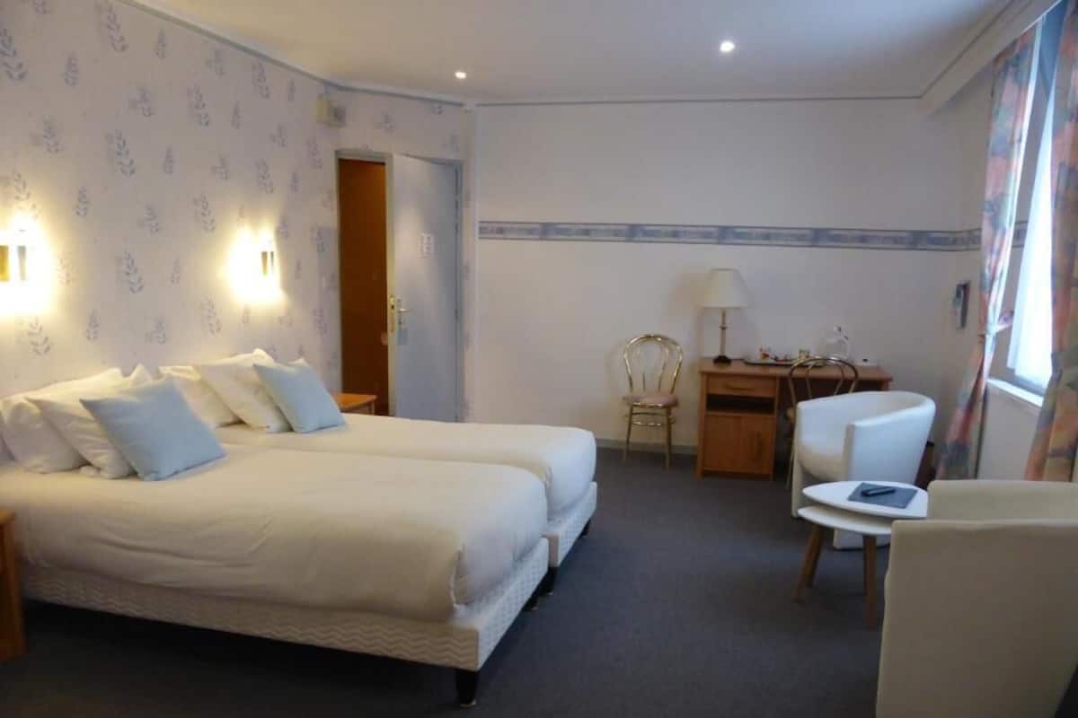 A hotel room with a double bed, a desk, a chair, and a lamp.