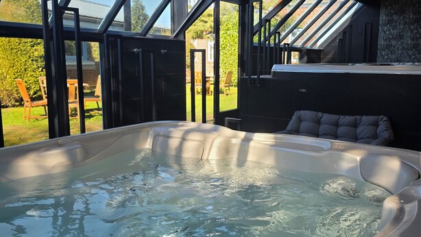 Un jacuzzi en una habitación moderna con tragaluces, vistas al exterior y una zona de estar con cojines.