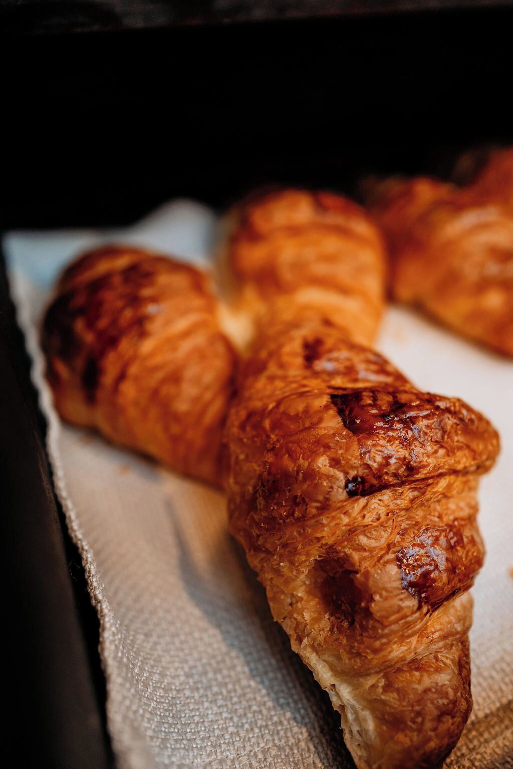 A close-up of a pastry, likely a croissant, with a glossy, golden-brown crust.