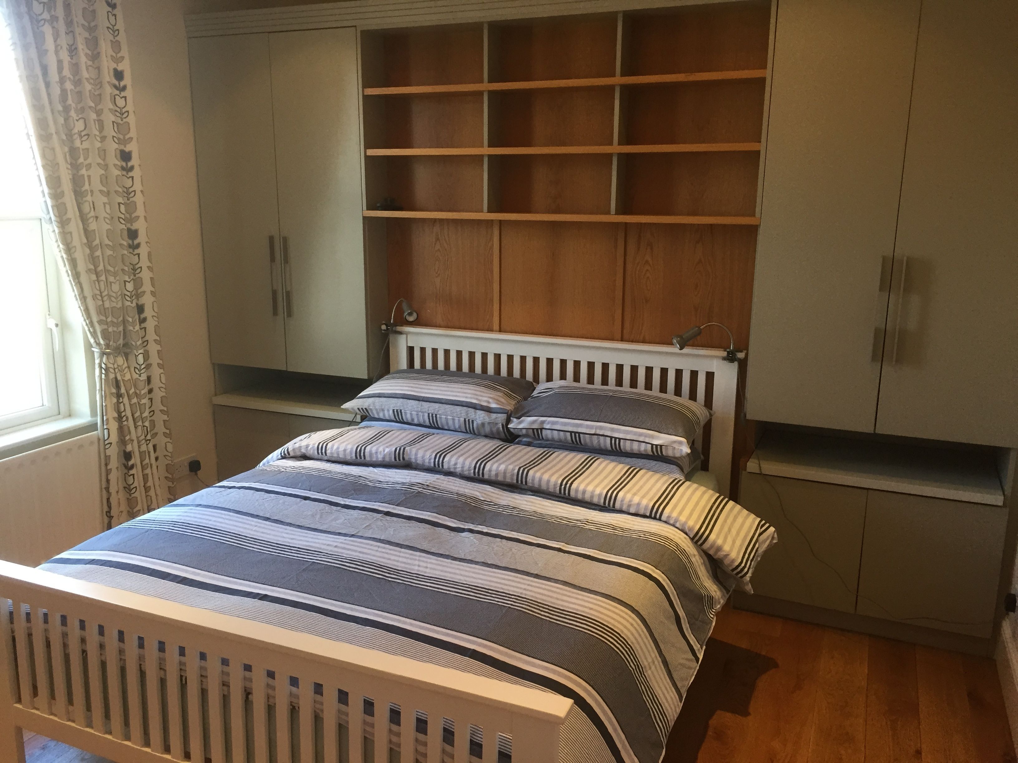 A bedroom with a bed, a wooden headboard, a bedside table, and built-in shelves.