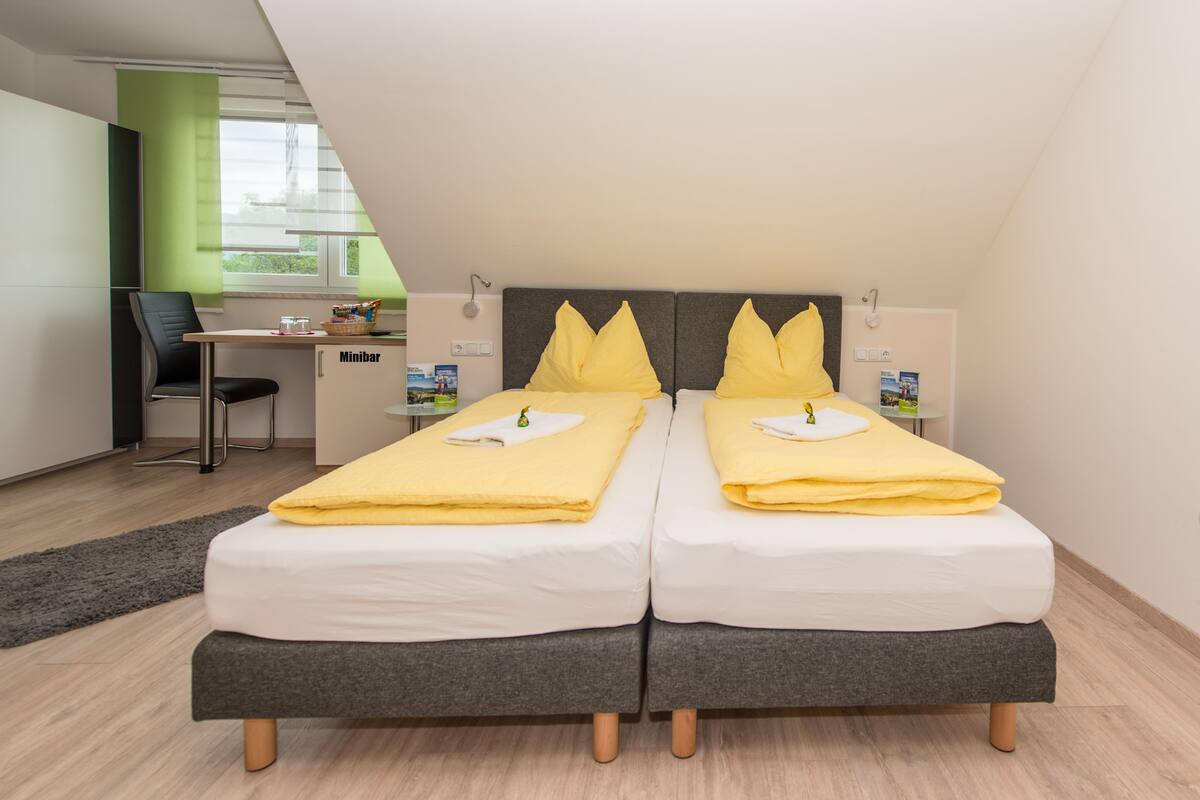 Una habitación de hotel moderna con dos camas individuales, un escritorio y una silla.