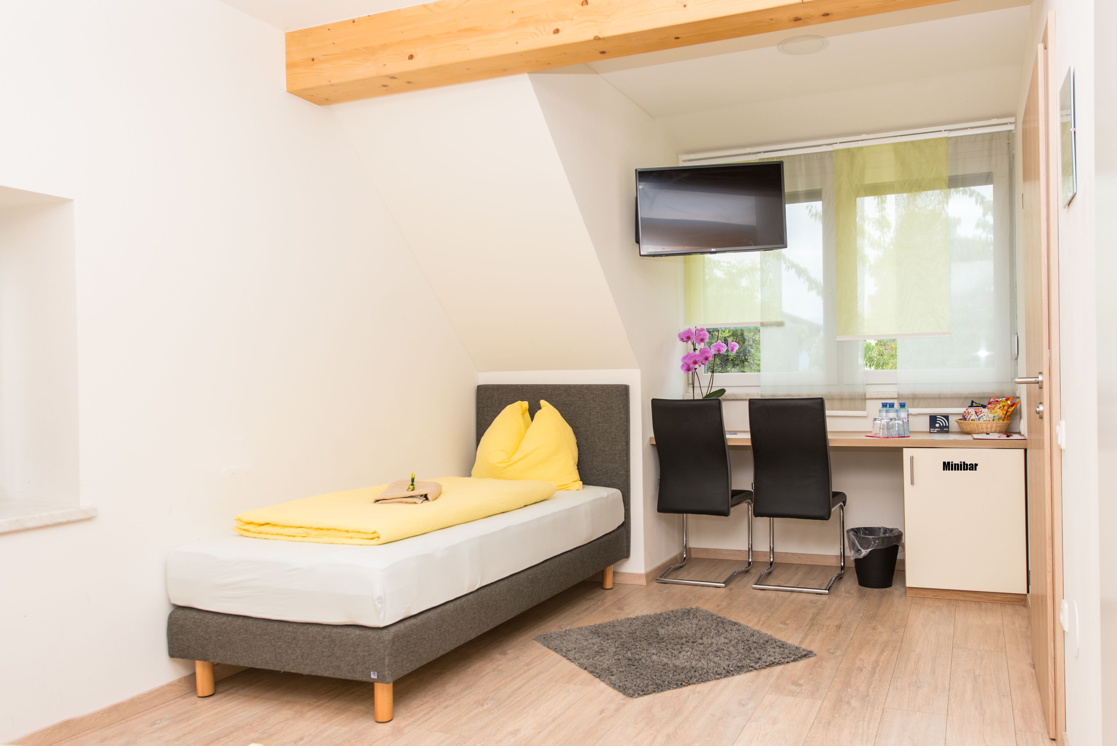 Una habitación pequeña con cama, escritorio y televisor.