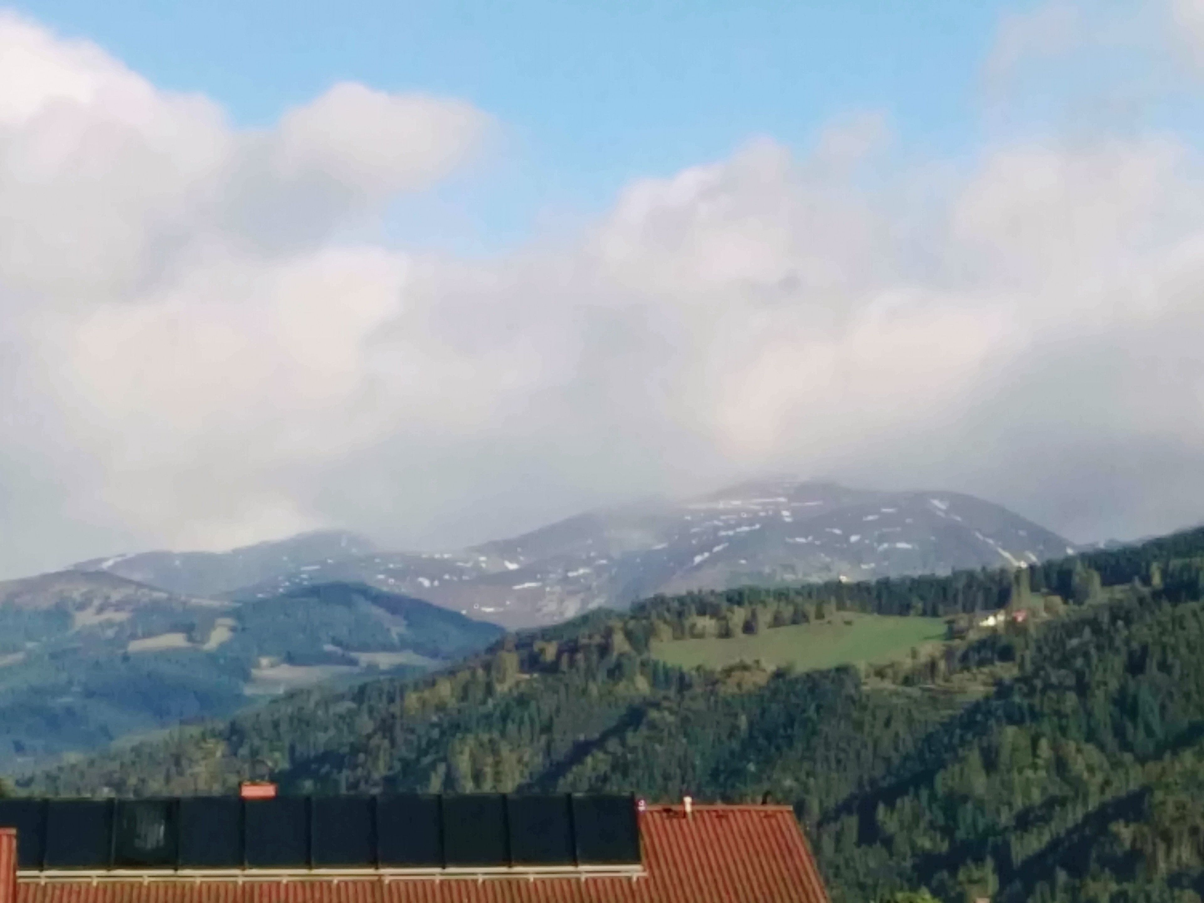 A mountainous landscape with a building featuring a long, flat roof and a visible chimney.