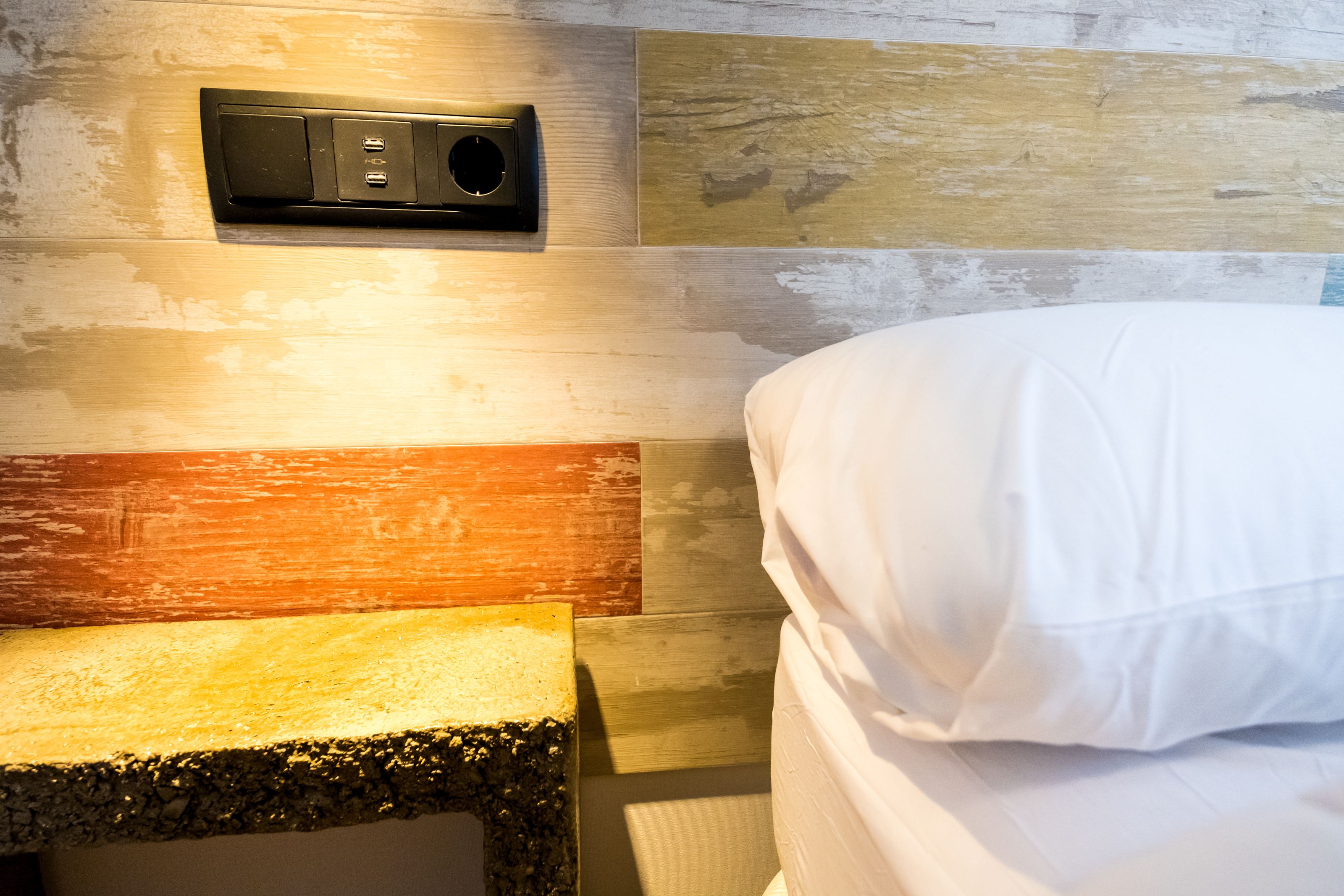 Une chambre à coucher avec un lit, une table de chevet et un haut-parleur fixé au mur.