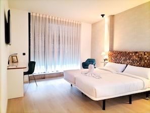 A hotel room with a bed, a desk with a chair, a TV, and a window with curtains. - Far Home Bernabeu (Madrid)