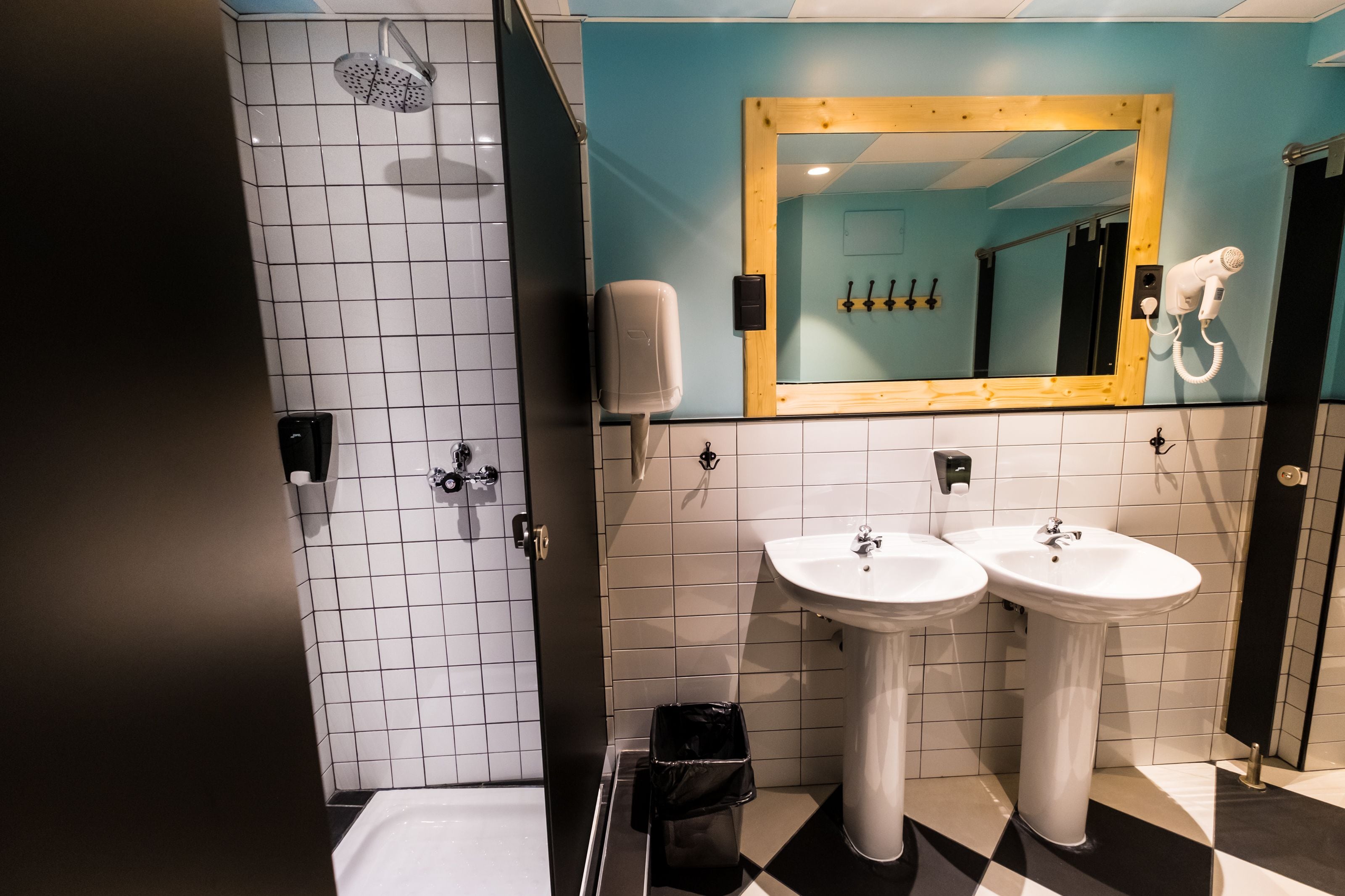 A bathroom with two sinks, a shower, and a mirror with a wooden frame.