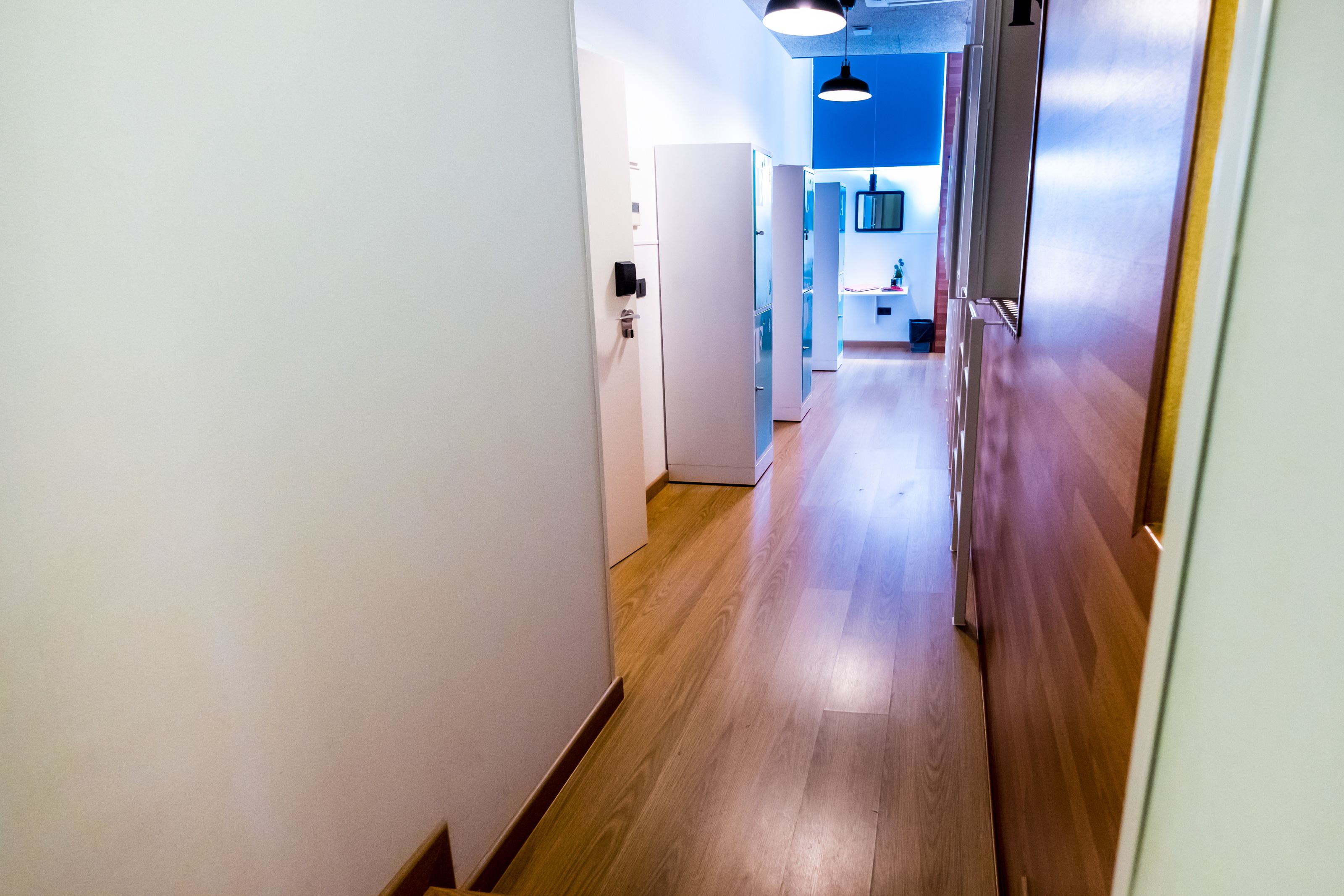 A narrow hallway with wooden flooring and white walls.