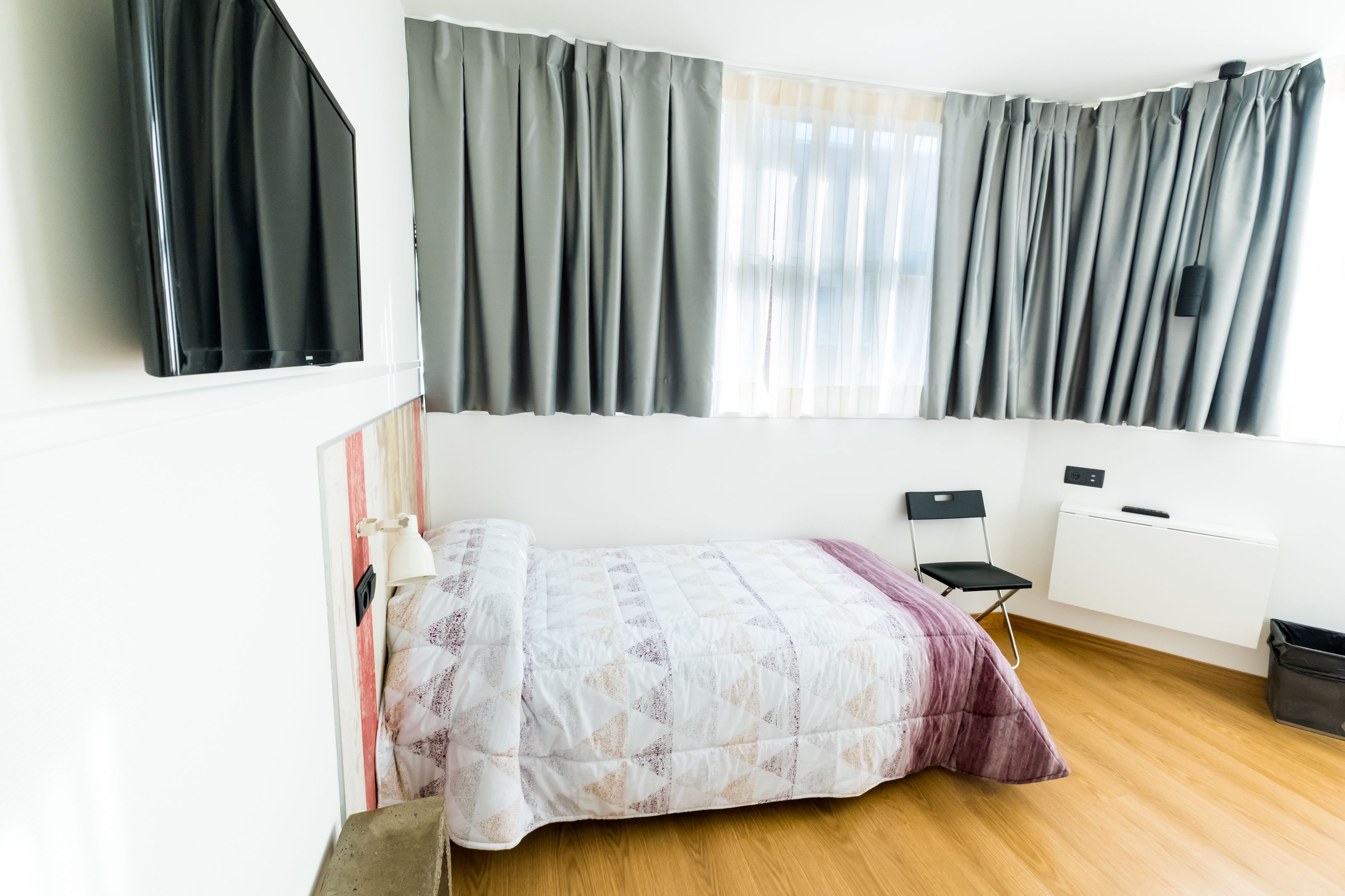 Un dormitorio con cama, una silla, un escritorio y un radiador.