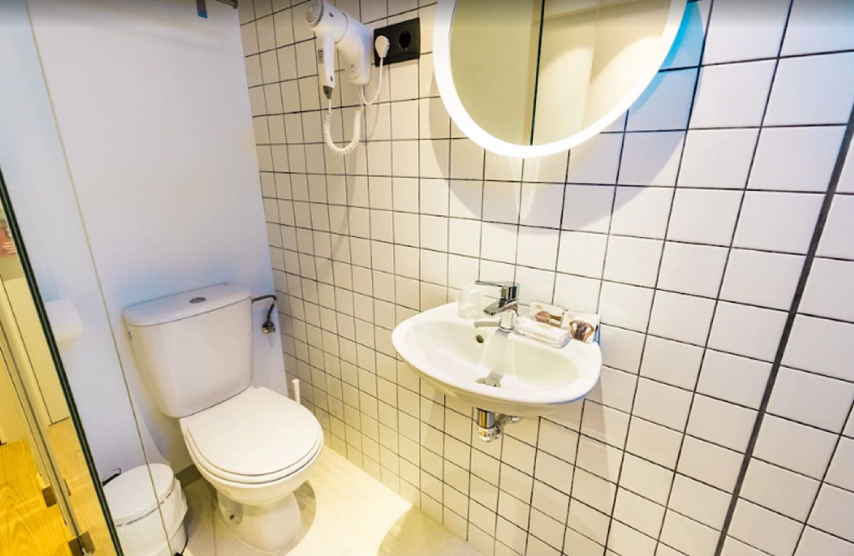 Un bagno piccolo e pulito, con il water, un lavandino e uno specchio.