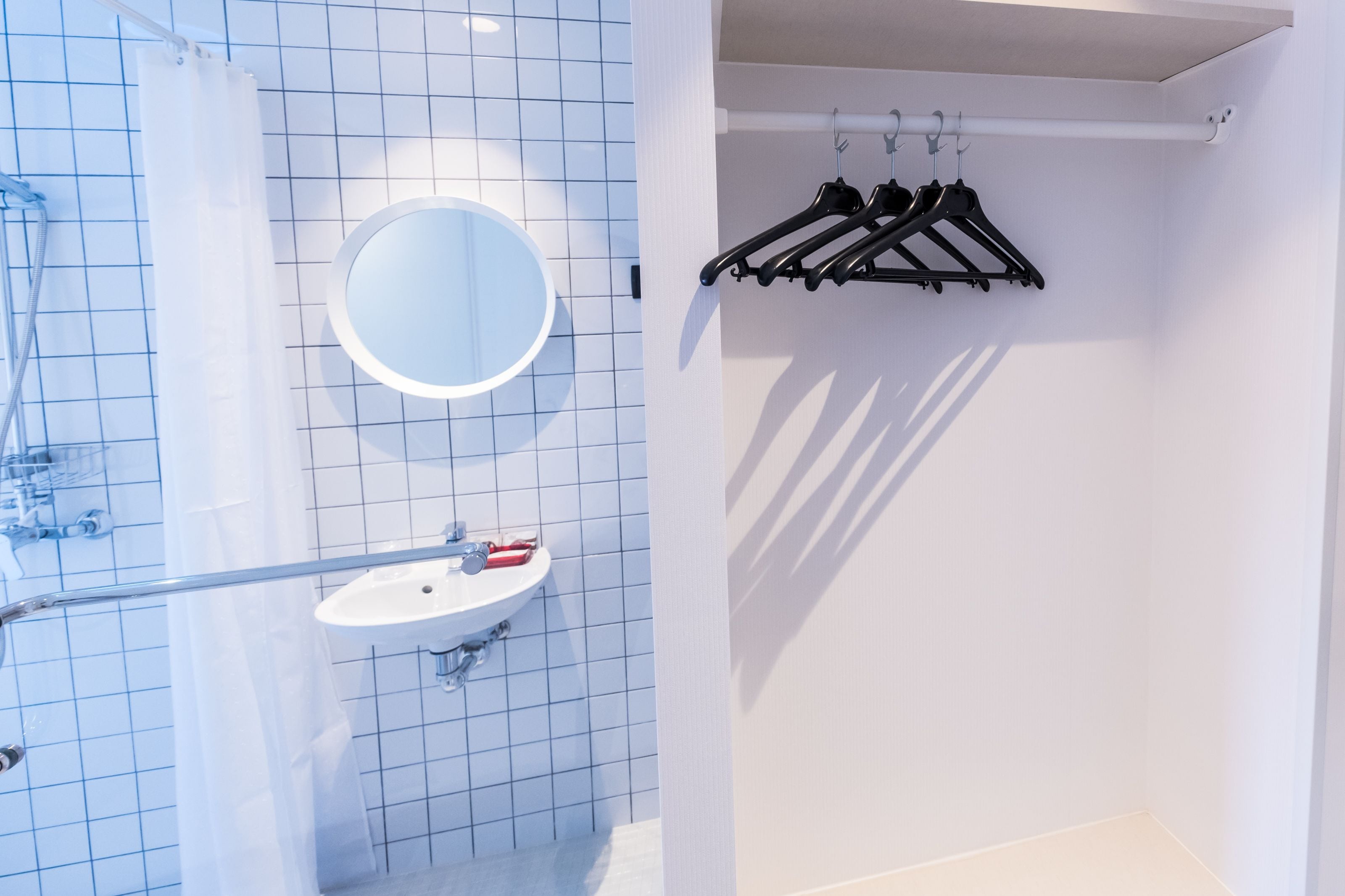 Une salle de bain avec un lavabo blanc, un miroir et une douche avec un rideau.