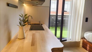 A modern kitchen with a built-in sink, a potted plant, and a view of the outdoors through a sliding glass door. - Far Home Bernabeu (Madrid)