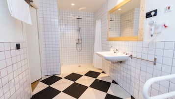 Un baño con ducha, lavabo, espejo y secador de manos.