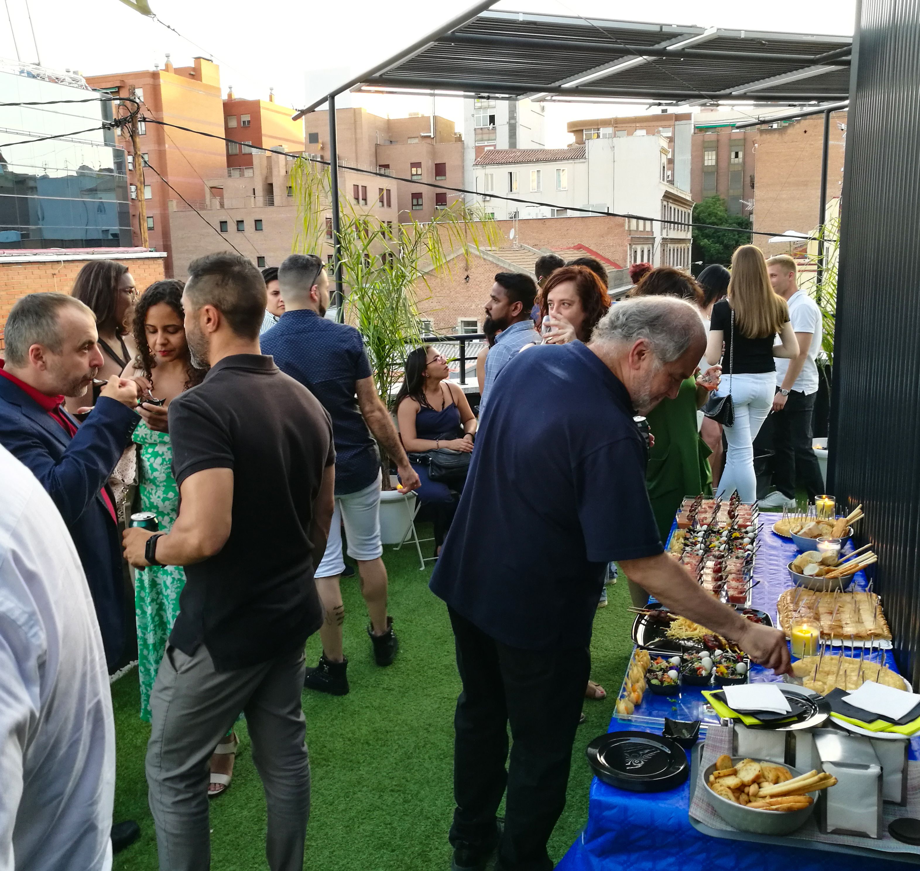 Un groupe de personnes participe à un événement en plein air, près d’une table de buffet.
