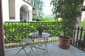 A balcony with a table and chairs, surrounded by a black metal fence and lush greenery. - Ca' Rosa Bed & Breakfast (Malnate)