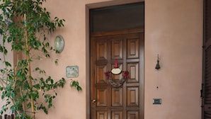 A wooden door with a welcome sign, a potted plant, a magazine, and a metal pot on the ground. - Ca' Rosa Bed & Breakfast (Malnate)