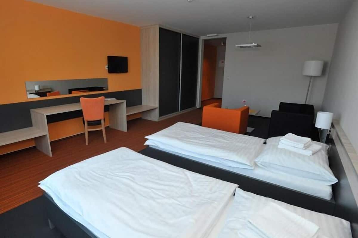 A hotel room with two beds, a desk, a chair, a TV, and a sliding door.