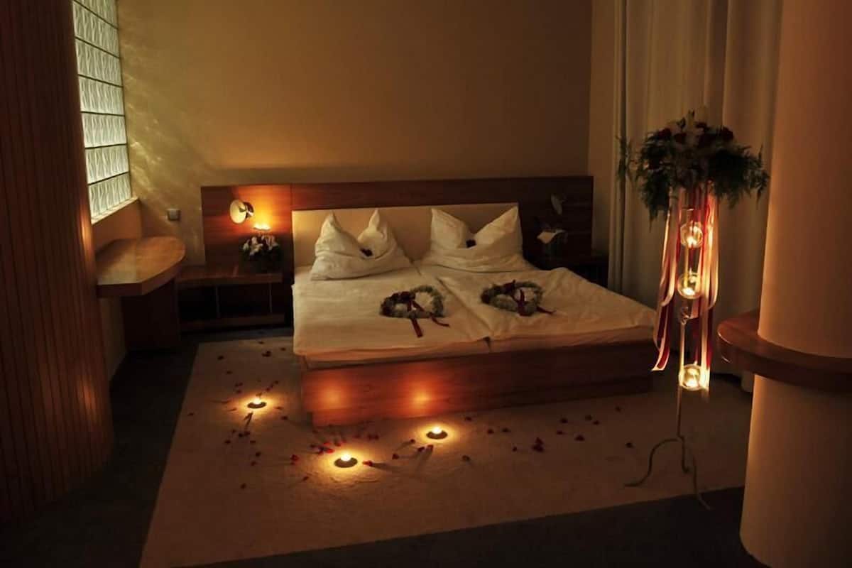 A neatly arranged bedroom with a large bed, bedside tables, a nightstand, and a potted plant.