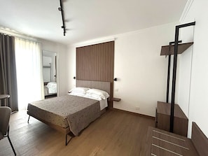 A bedroom with a bed, a chair, a mirror, and a wooden headboard. - I Cordari B&B (Vieste)
