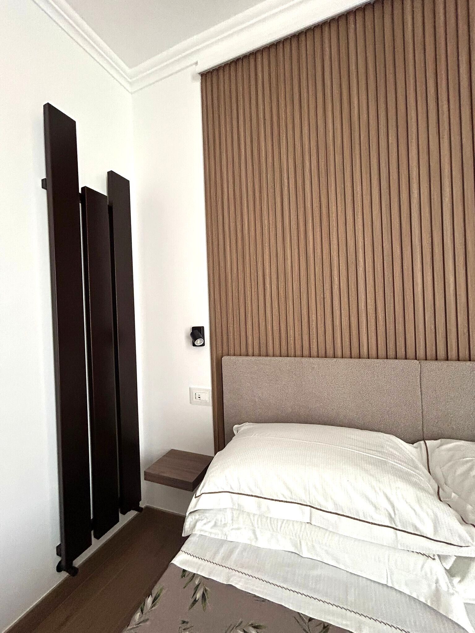 Habitació d'hotel amb un llit, un radiador fixat a la paret i una finestra amb persianes verticals.
