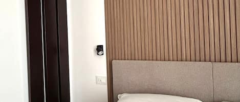 A hotel room with a bed, a wall-mounted radiator, and a window with vertical blinds.