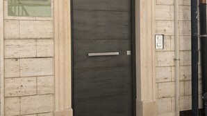 A dark wooden door with a metal handle, set in a beige frame, against a wall with a sign above it. - I Cordari B&B (Vieste)