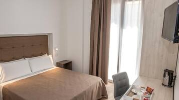 Une chambre d’hôtel avec un grand lit, un bureau avec une chaise, une télévision et une machine à café.