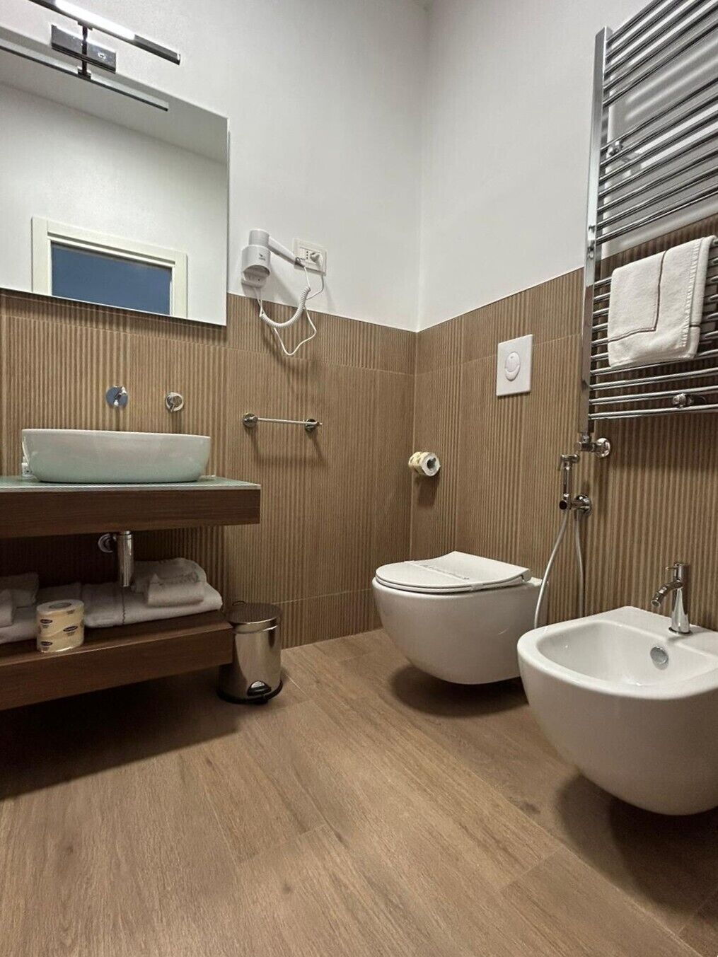 Ein Badezimmer mit Waschbecken, Toilette, Bidet, Handtuchhalter und einem Spiegel.