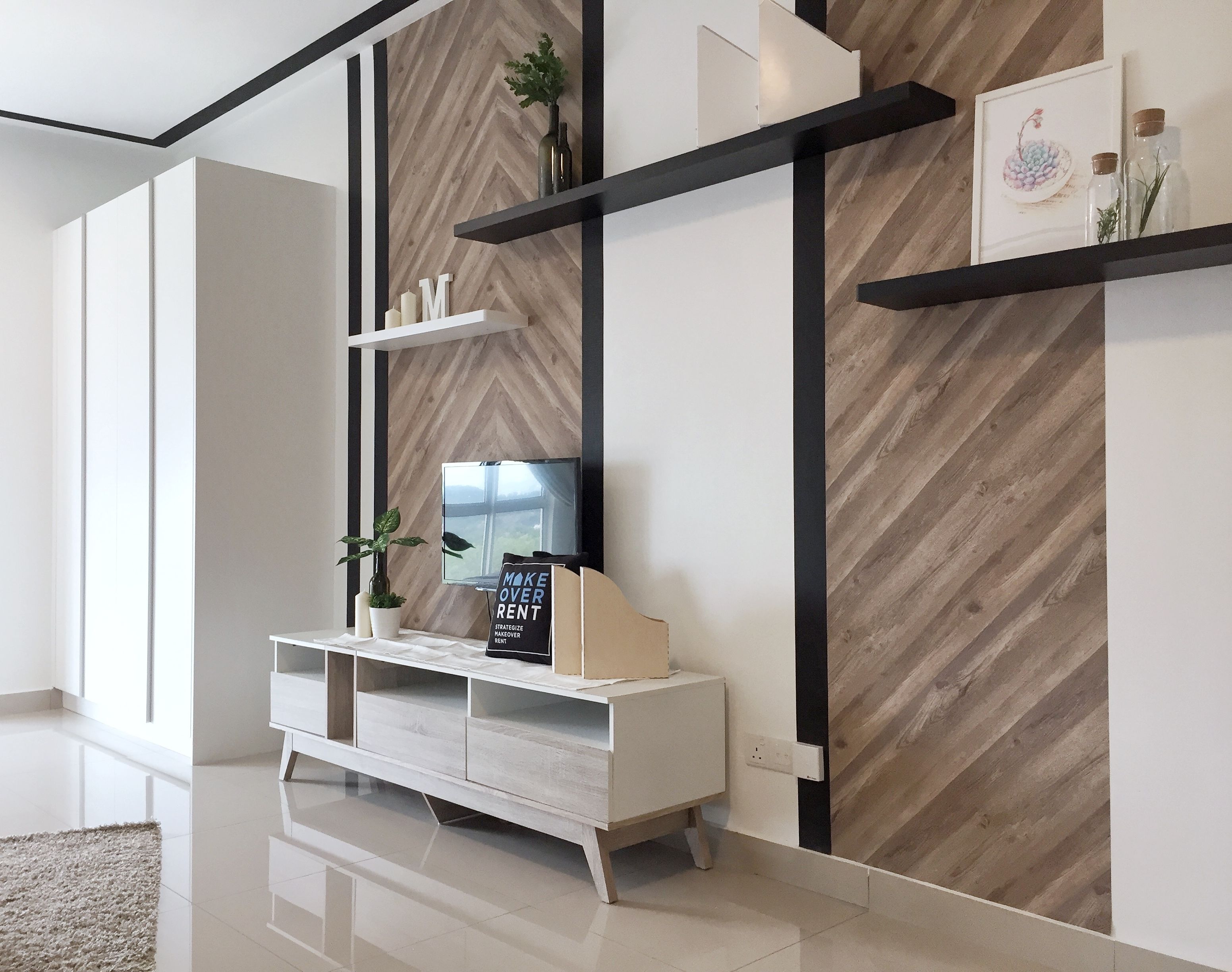 A modern living room with a white entertainment unit, a large mirror, and a herringbone wood wall.