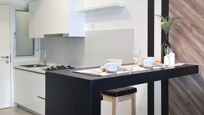 Cozinha moderna com ilha central, luminárias pendentes pretas e uma parede de destaque em madeira.