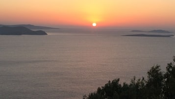 A sunset over a calm sea with distant landforms.