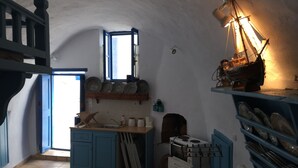 A compact kitchen with blue cabinets, a small stove, and a window. - Medieval Memory House (Astypalaia)