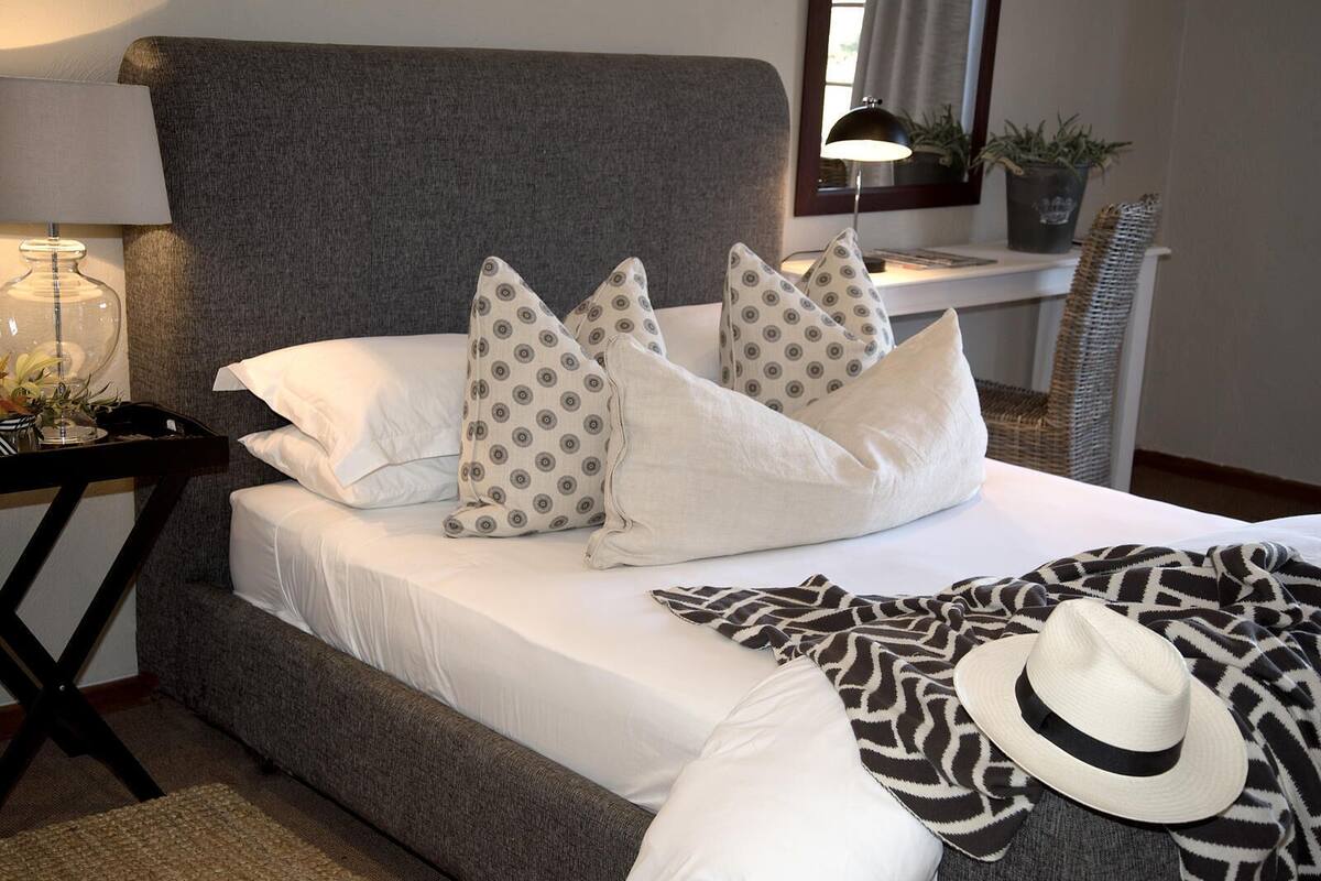 Una cama con almohadas estampadas, un sombrero y una manta.