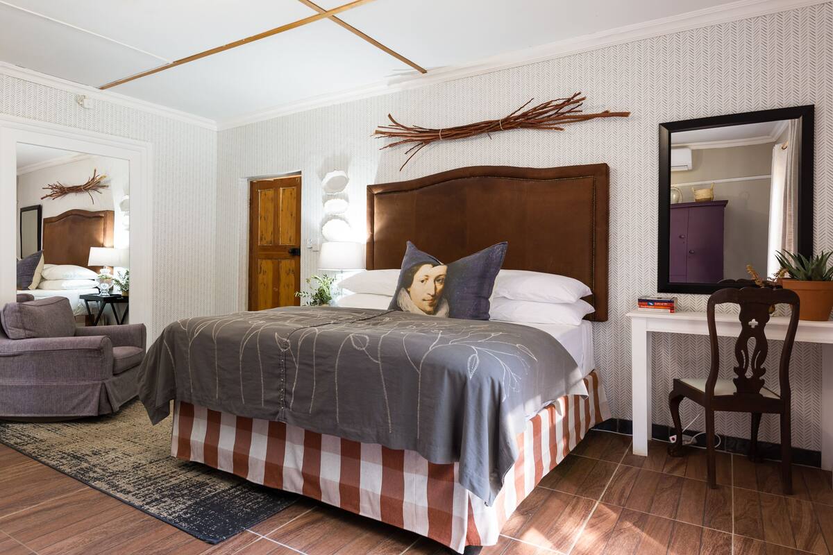 Un dormitorio con una cama grande, una silla, un escritorio y un espejo.