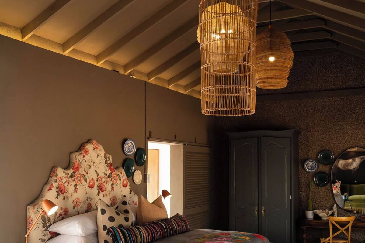 Un dormitorio con cama, mesita de noche, lámpara y una lámpara colgante.