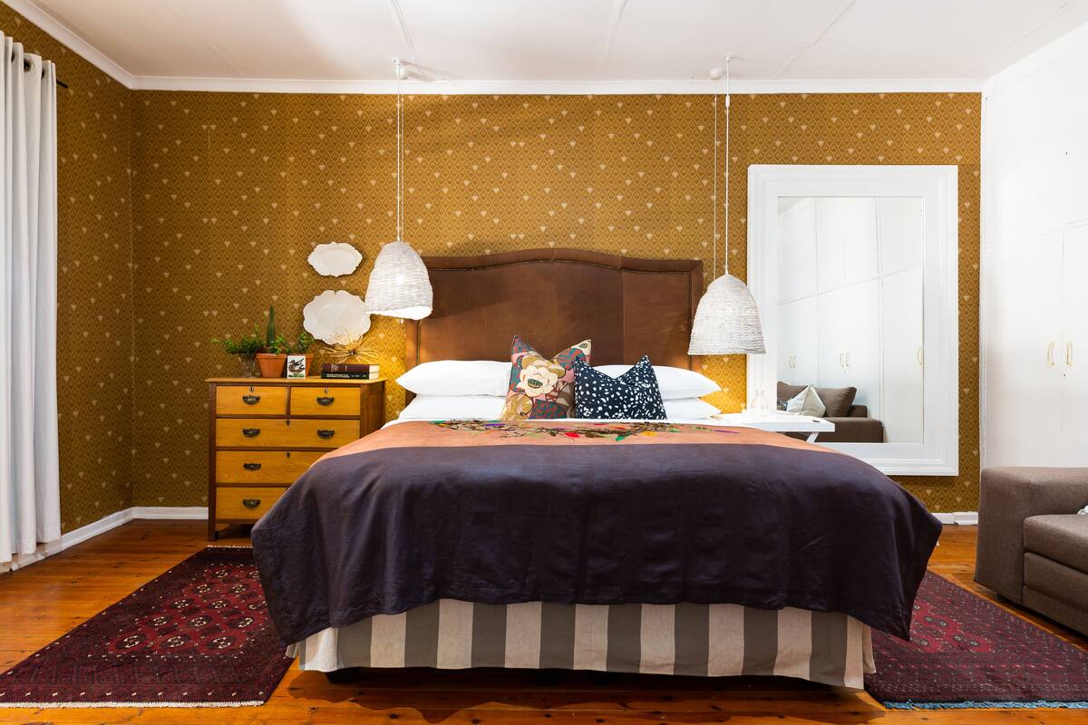 Un dormitorio con una cama grande, un aparador, una mesita de noche y una ventana con cortinas.