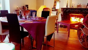 A dining area with a table set for four, chairs, a fireplace, and artwork on the walls.