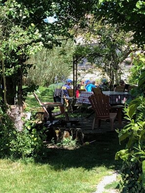 Un espacio al aire libre con mesas y sillas, rodeado de follaje y árboles.