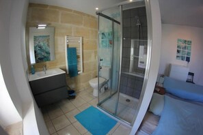 Un baño con cabina de ducha de vidrio, un lavamanos blanco y un inodoro.