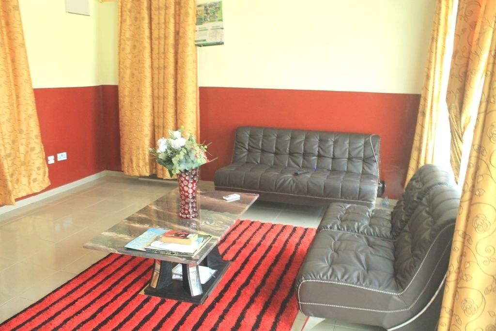 Un salon avec un canapé, une table basse en verre et un tapis rayé rouge et noir.