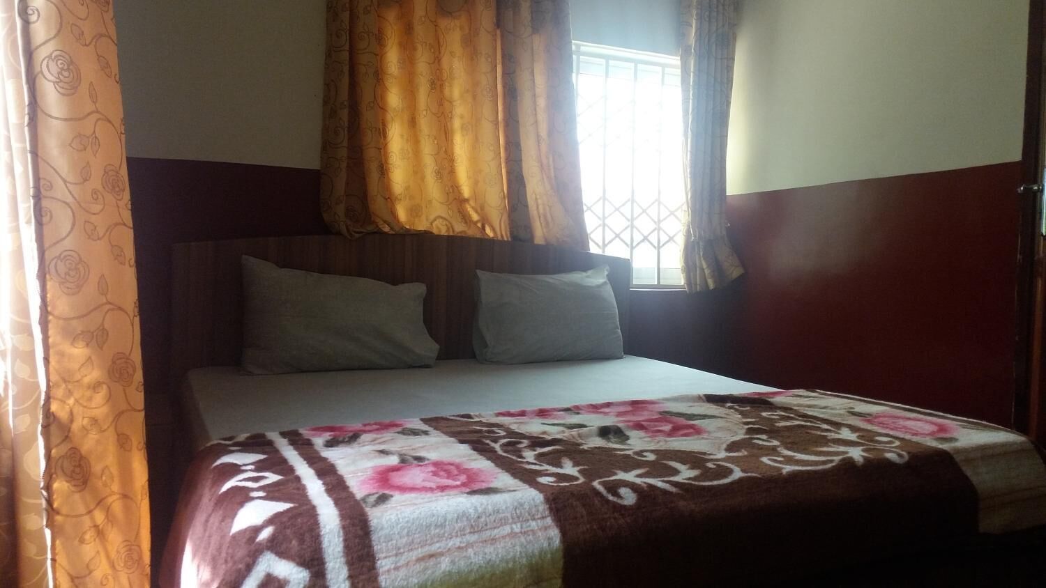 A bed with a floral bedspread, a headboard, and two pillows.