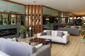 A spacious living area with a fireplace, multiple sofas, and a large mirror reflecting the room. - Grand Keskin Hotel (Denizli)