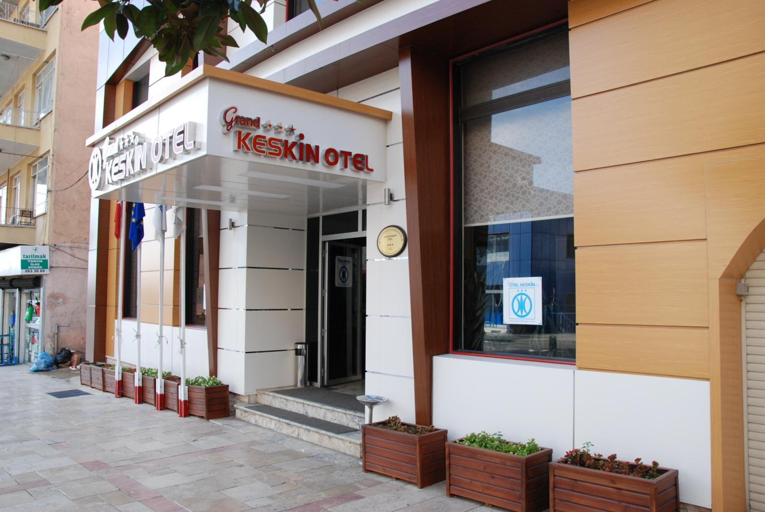 The exterior of the Keskin Hotel with a modern facade, a visible entrance, and potted plants at the entrance.