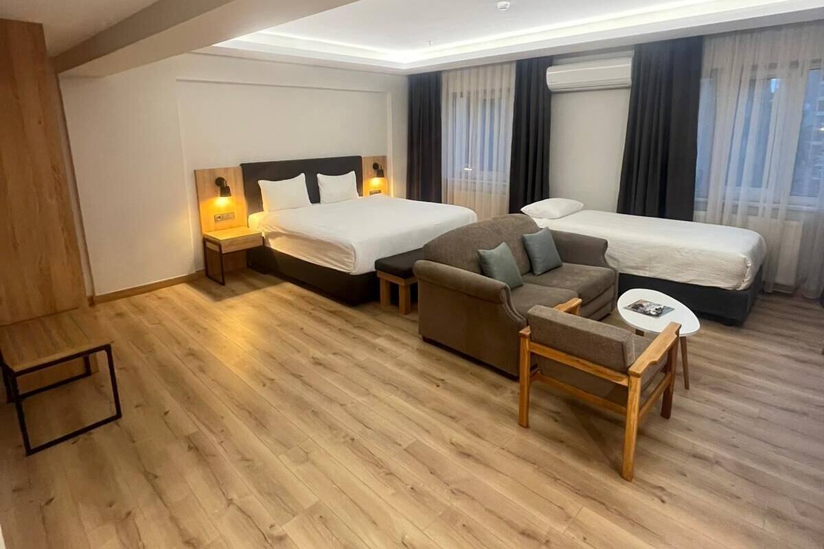 Une chambre d’hôtel moderne avec deux lits, un canapé, une petite table et un plancher en bois.