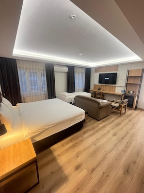 Une chambre d’hôtel moderne équipée d’un grand lit, d’un canapé, d’un bureau et d’une télévision.