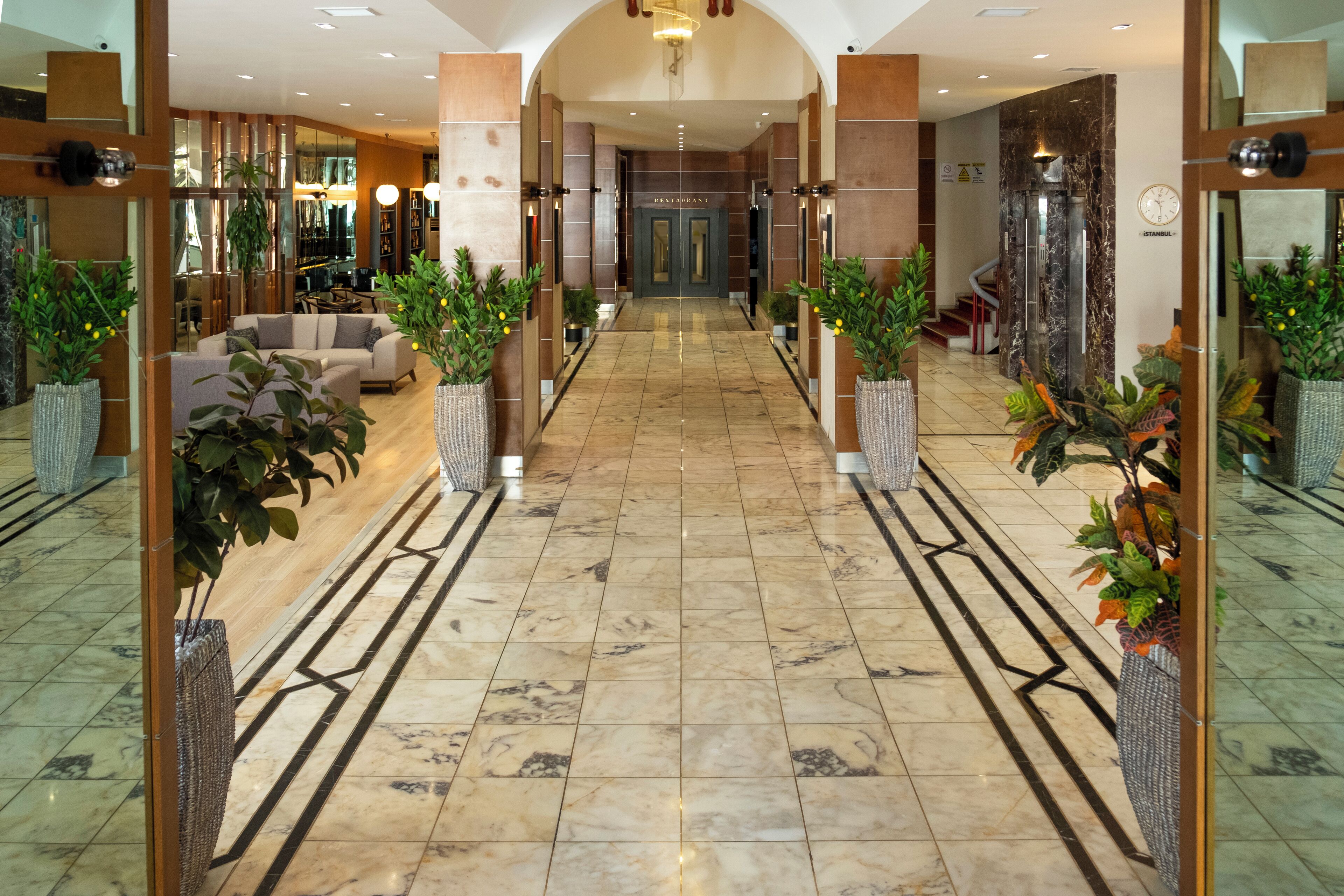 A hotel lobby with a marble floor, a sofa, and potted plants.