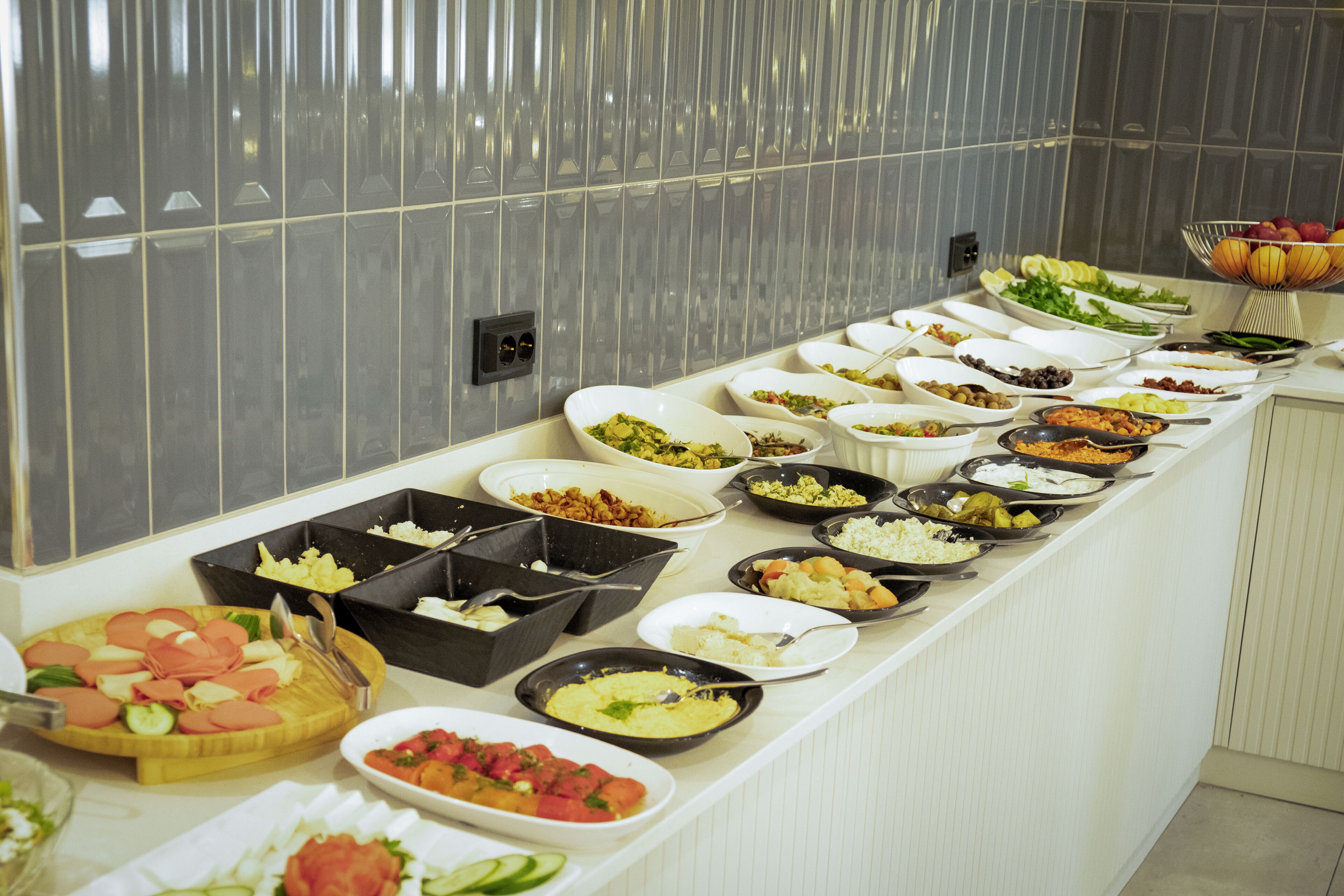 A buffet with various dishes and a fruit bowl.