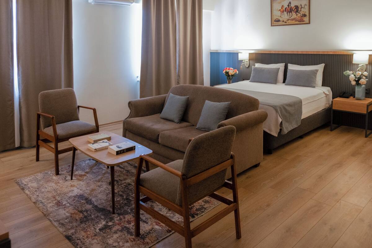 Une chambre d’hôtel comprenant un lit, un canapé, une table basse et deux fauteuils.