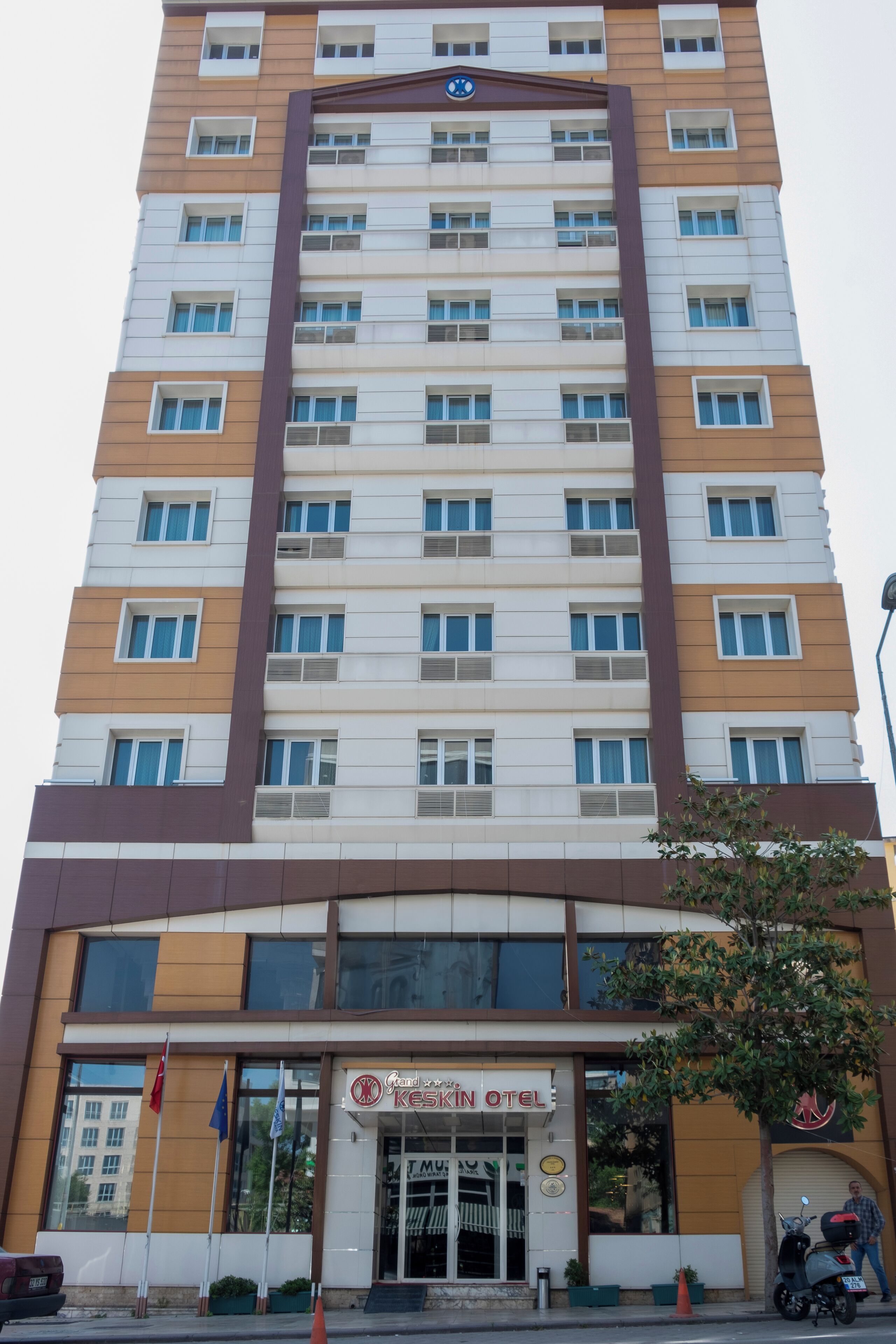 Un hotel de varios pisos con un diseño moderno, que presenta una entrada destacada con fachada de vidrio y el letrero de 'Keskin Hotel'.