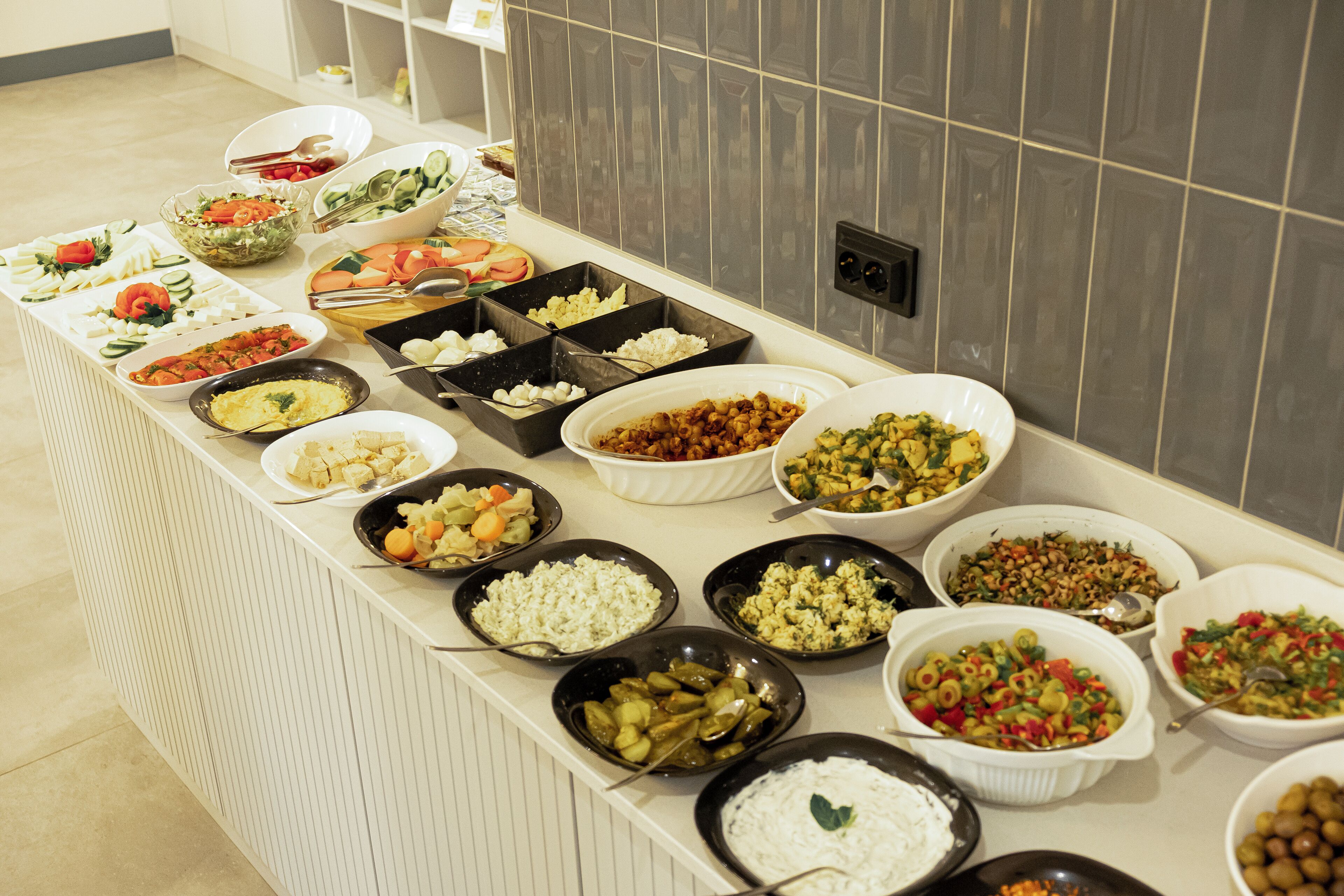 A buffet table with various food items and bowls.