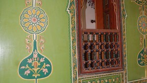 A room with green walls, a decorative window with a grid of bottles, and intricate floral patterns. - Museum House - Dar Melyani (Fes)
